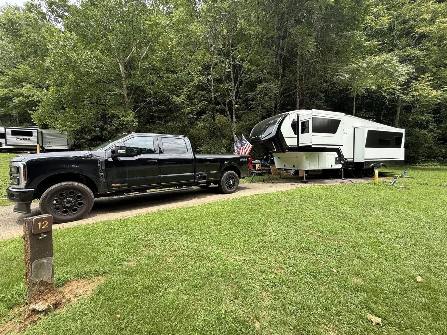 Our F-350 and fifth-wheel RV at a wooded campground, ready for the road